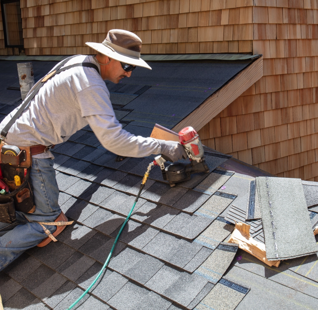 Construction worker fixing roof shingles