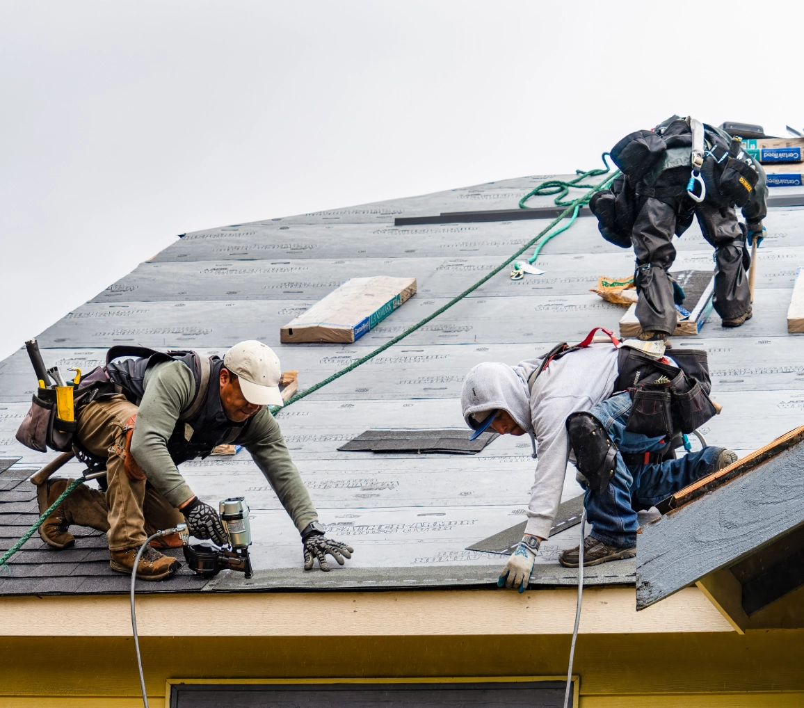 Construction team working on rooftop shingles