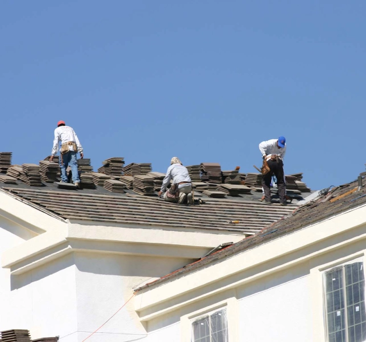 Construction workers repairing roof shingles.