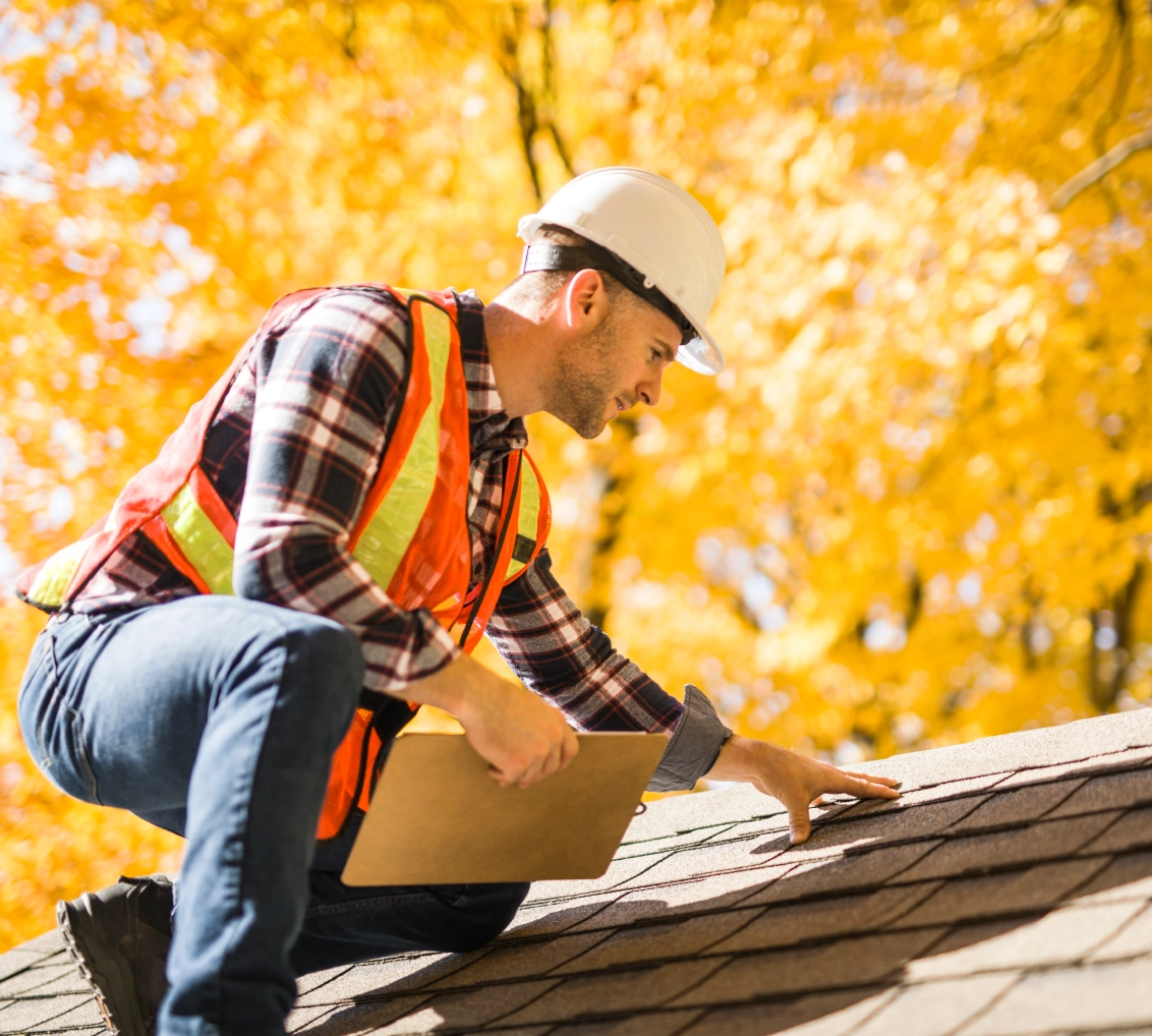 Roofer inspecting shingles in autumn
