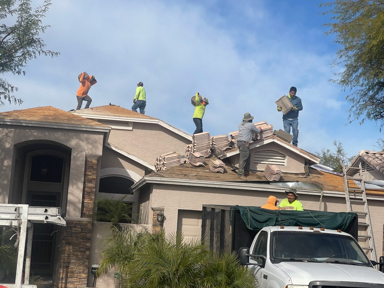 Workers demolishing a roof on a sunny day.
