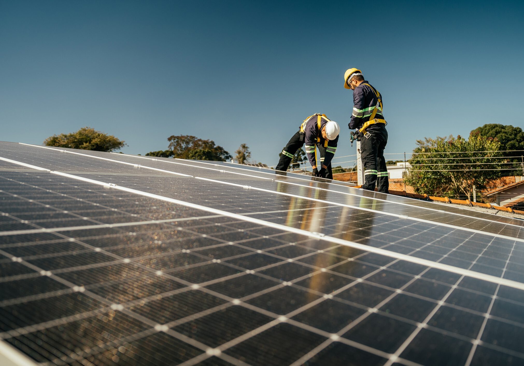 Workers installing solar panels under a clear blue sky.