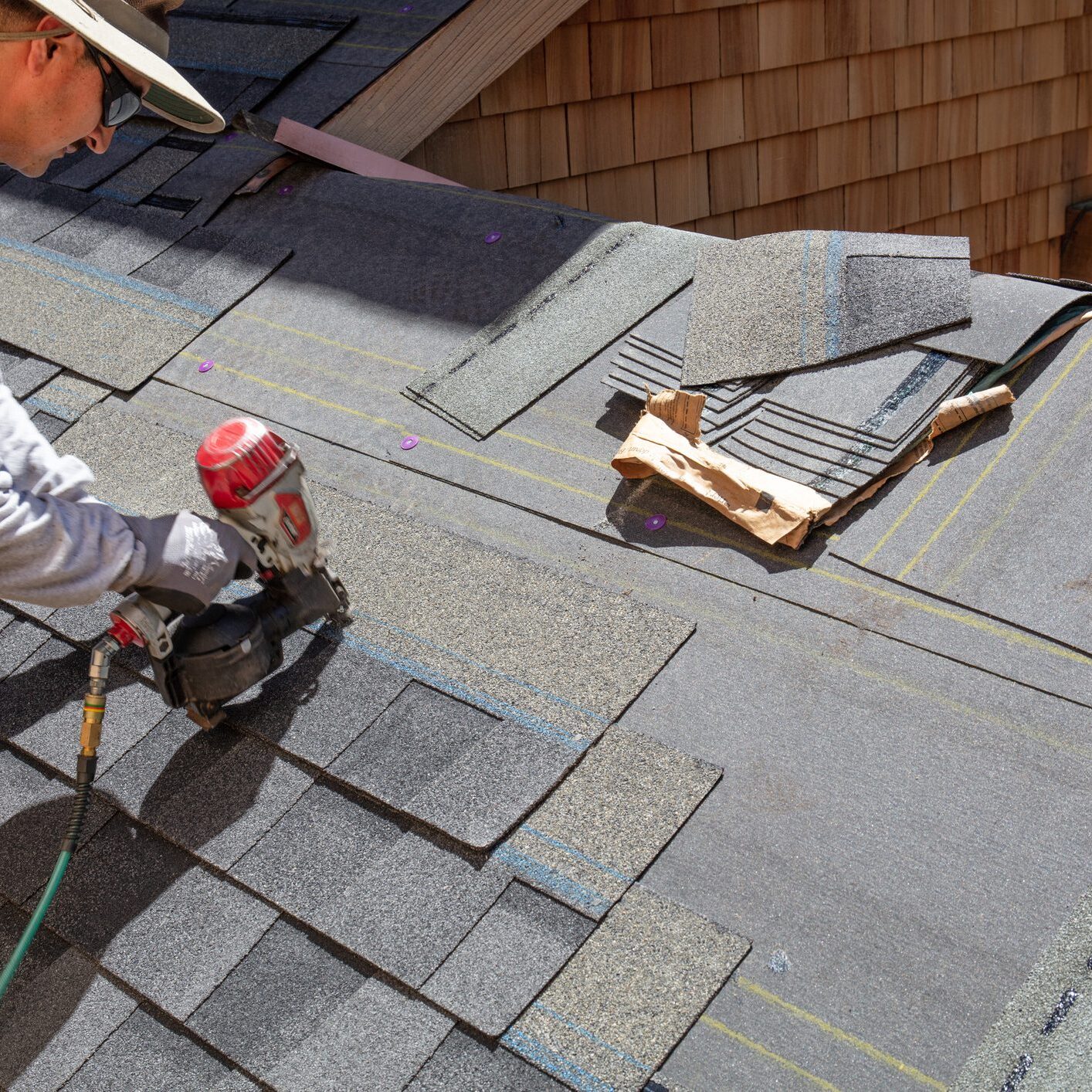 Worker installing asphalt shingles on a roof.